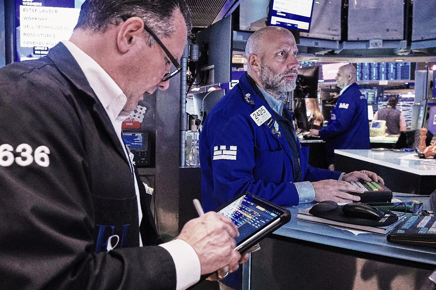 Trader Edward Curran, left, and specialist Meric Greenbaum, center, work on the floor of the New York Stock Exchange, Friday, May 22, 2026. (AP Photo/Richard Drew)