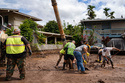 Volunteers assist in clearing mud using heavy equipment in a flooded residential neighborhood, Tuesday, March 24, 2026, in Waialua, Hawaii. (AP Photo/Mengshin Lin)