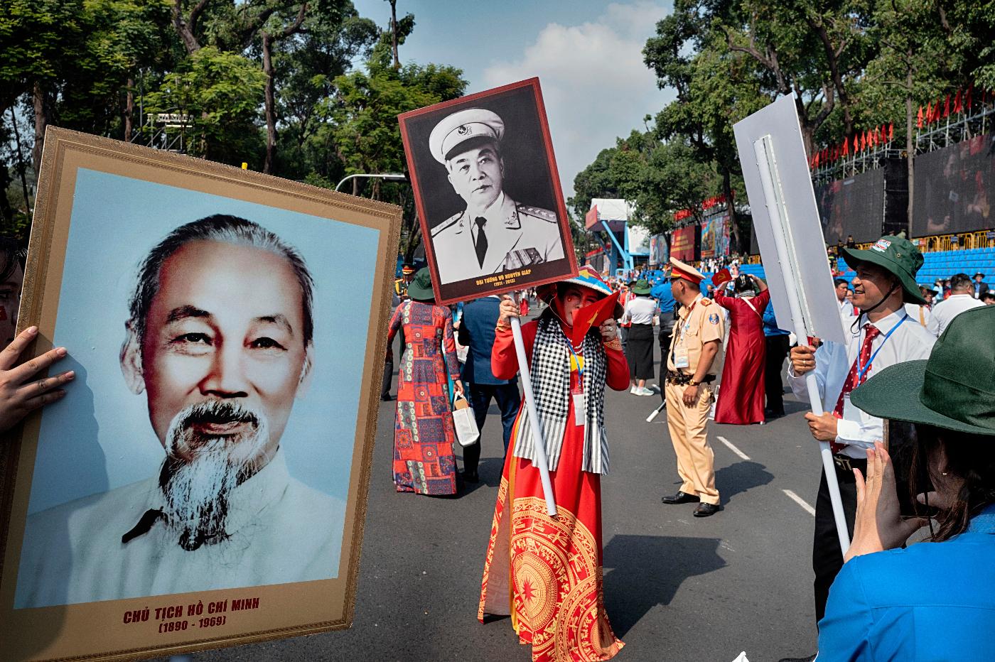 A woman is photographed with a photo of the late wartime Vietnamese Gen. Vo Nguyen Giap as another person holds a photo of the late Vietnamese revolutionary leader Ho Chi Minh, left, after a parade celebrating the 50th anniversary of the end of the Vietnam War on Wednesday, April 30, 2025, in Ho Chi Minh City, Vietnam. (AP Photo/Richard Vogel)