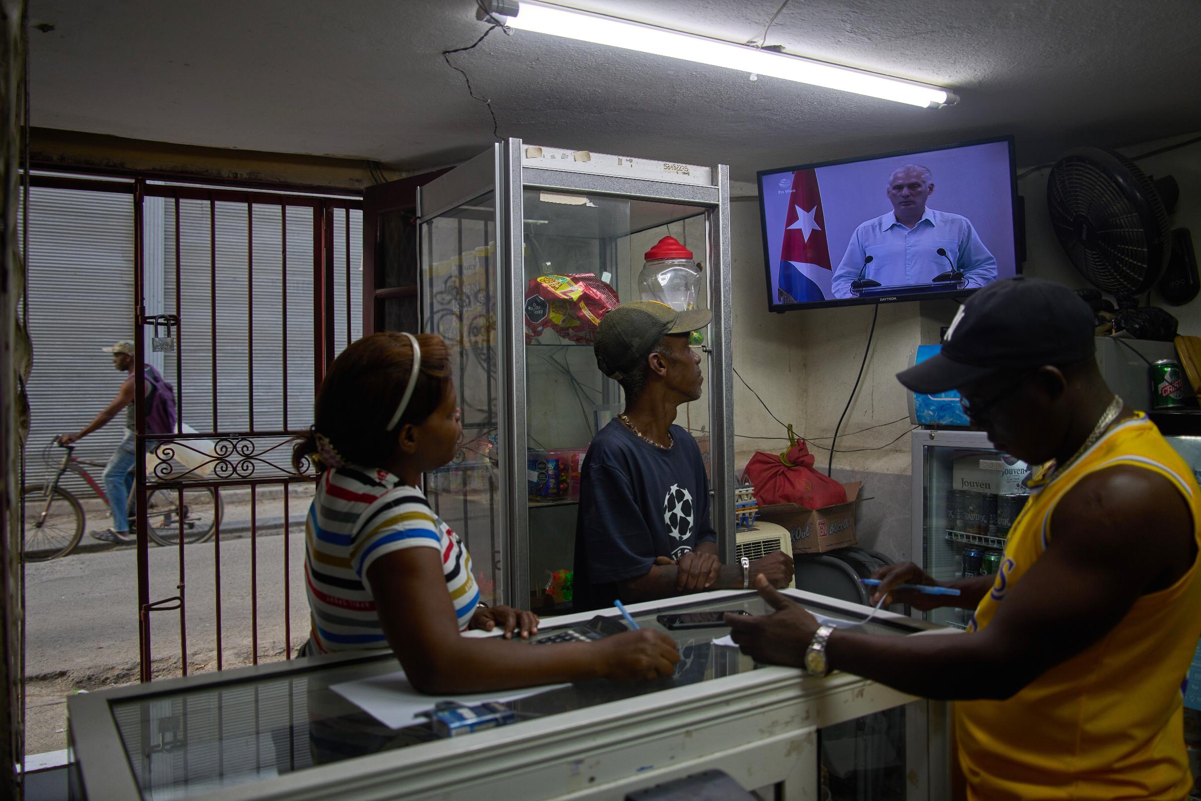 People inside a private convenience store see Cuban President Miguel Diaz-Canel speaking on TV in Havana, Cuba, Friday, March 13, 2026. (AP Photo/Ramon Espinosa)