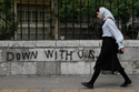 A woman walks past an anti-U.S. graffiti painted on the wall of the Tehran University on Enqelab-e-Eslami (Islamic Revolution) street in downtown Tehran, Iran, Saturday, April 25, 2026. (AP Photo/Vahid Salemi)