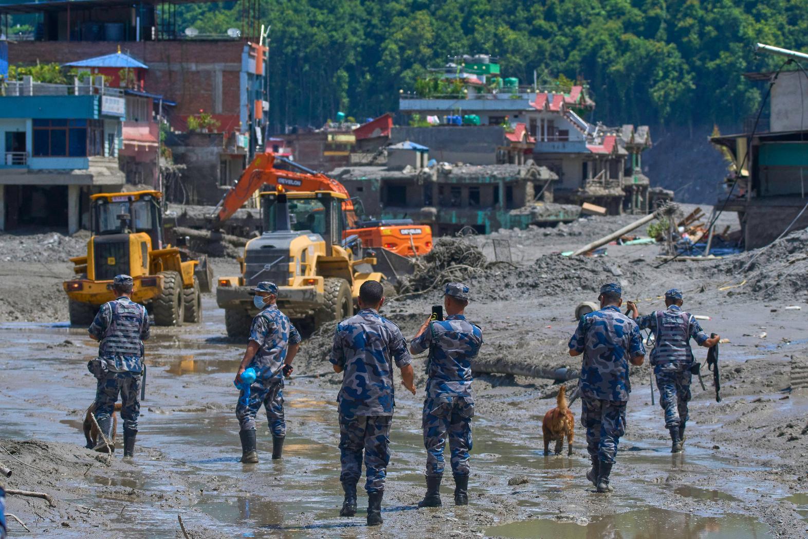 Nepalese policemen watch as earthmovers clear the debris of flash flooding in Nepal's Nuwakot district, Thursday, Aug. 27, 2026. (AP Photo/Niranjan Shrestha)