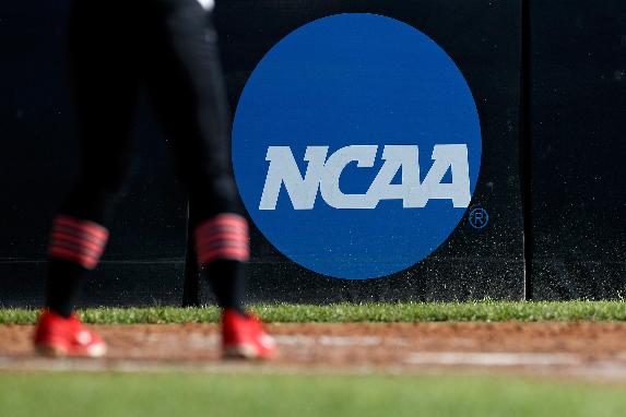 FILE - An athlete stands near an NCAA logo during a softball game in Beaumont, Texas, April 19, 2019. Two years after the NCAA cleared the way for college athletes to earn money off their fame and celebrity, digital technology is allowing some of them to get paid by their fans without having to do very much in return. Brent Chapman runs a platform called myNILpay. The app allows fans to choose a college athlete and send them money; the app then sends a notification to the athlete's school email. The athlete fills out a form and the money is then transferred via Venmo or a similar payment method. In exchange, the fan receives a unique computer-generated piece of “art” with the athlete's signature on it. Chapman said that serves as the quid pro quo. (AP Photo/Aaron M. Sprecher, File)