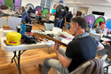 Music repair coach James Dean Conklin helps people fix their instruments at a Repair Cafe in New Paltz, N.Y., May 23, 2026. (AP Photo/Michael Weissenstein)