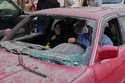Family members ride in a damaged car, as they flee the site of an Israeli airstrike that hit an apartment building in the southern port city of Sidon, Lebanon, Friday, March 13, 2026. (AP Photo/Mohammed Zaatari)