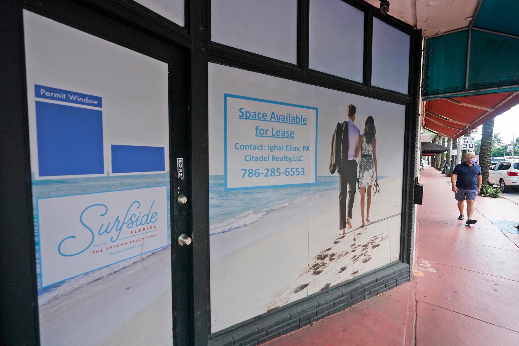A pedestrian walks past an empty business available for lease, Monday, Oct. 12, 2020, in downtown Surfside, Fla. (AP Photo/Wilfredo Lee)