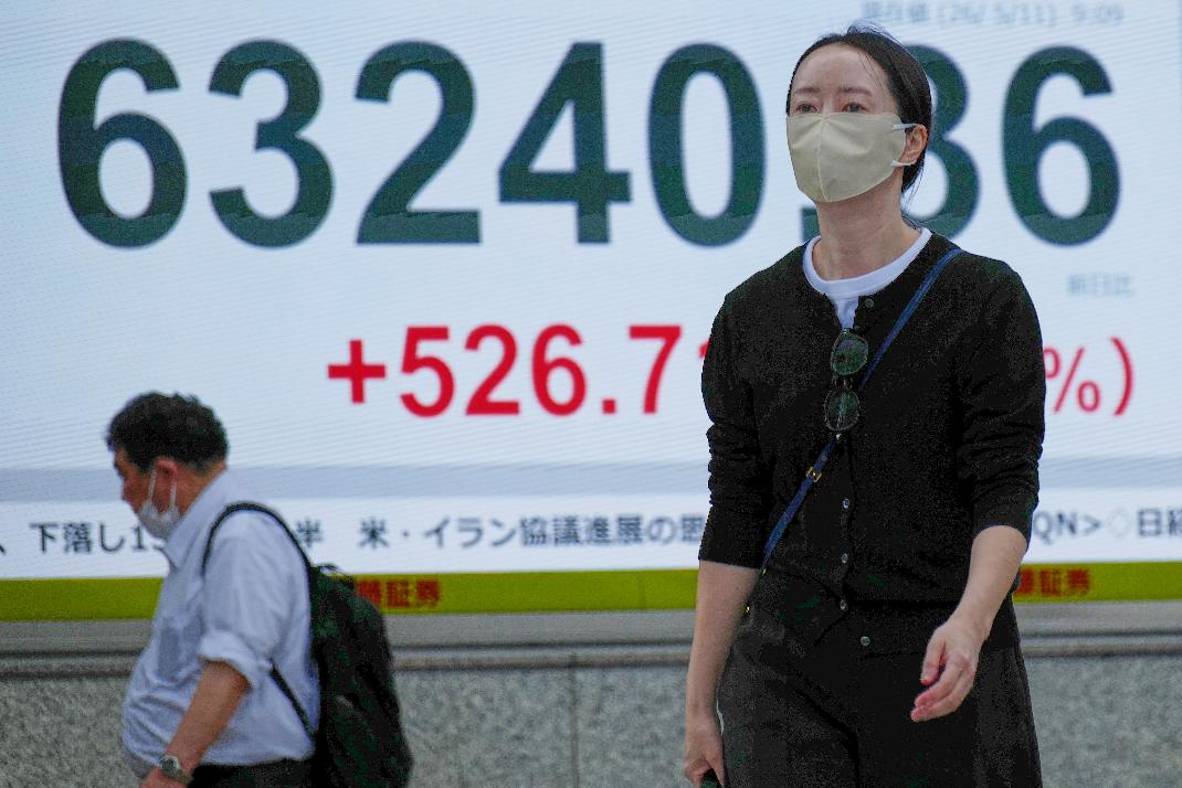 People walk in front of an electronic stock board showing Japan's Nikkei index at a securities firm Monday, May 11, 2026, in Tokyo. (AP Photo/Eugene Hoshiko)
