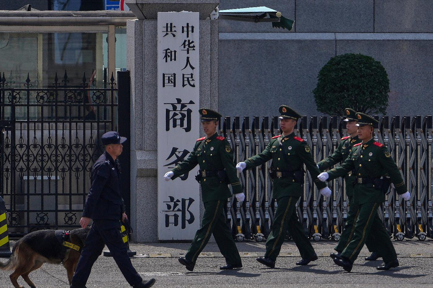 FILE - Paramilitary soldiers and a police officer with a sniffer dog march past the main entrance gate of China's Ministry of Commerce, in Beijing, on April 3, 2025. (AP Photo/Andy Wong, File)