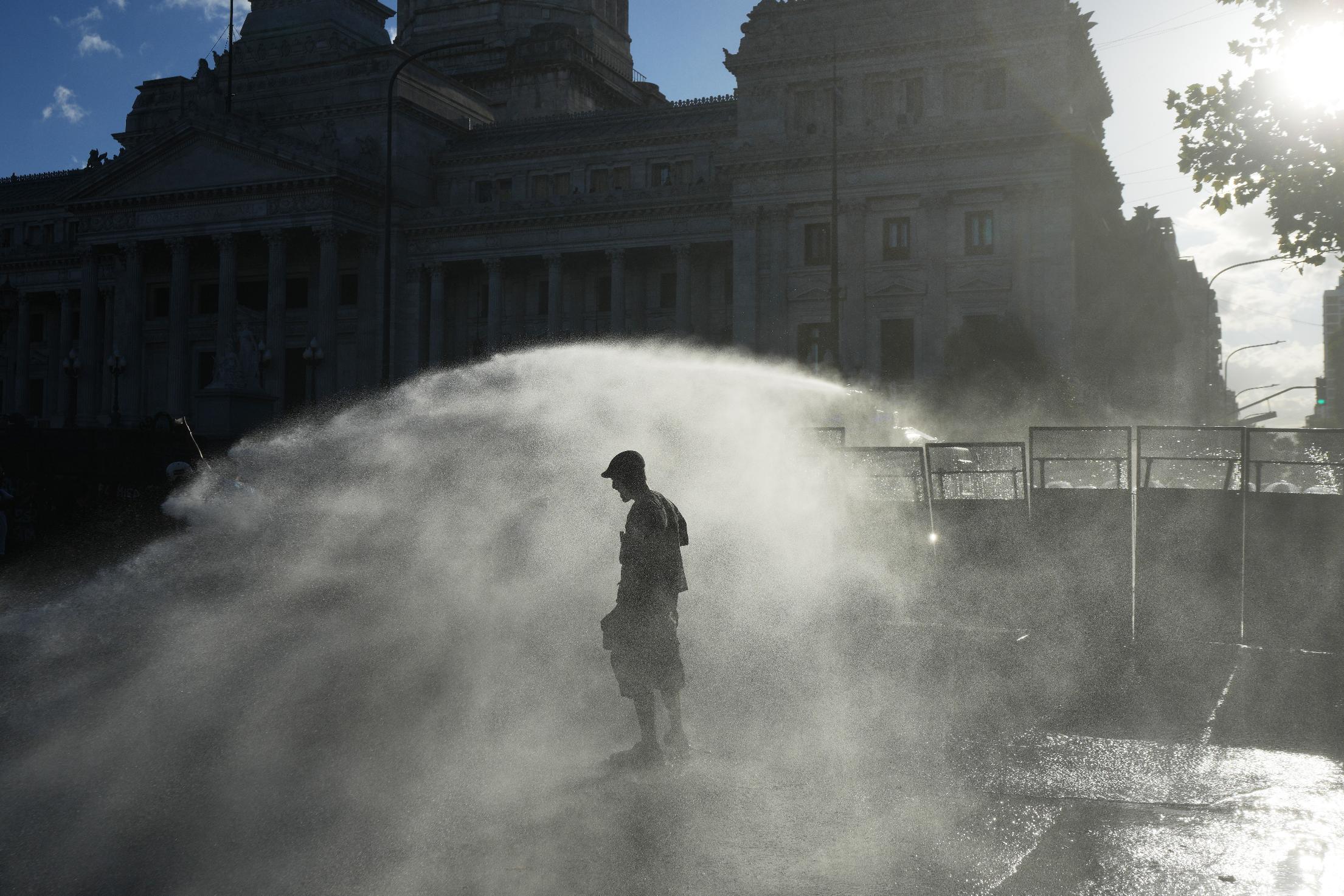 Protesters are sprayed by a police water cannon in front of Congress during a march by trade unions and opposition groups against a labor reform bill proposed by President Javier Milei's government in Buenos Aires, Argentina, Thursday, Feb. 19, 2026. (AP Photo/Rodrigo Abd)
