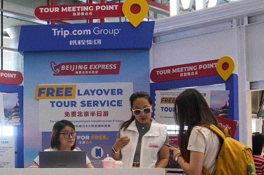 Workers attend to a traveller at a travel agency Trip.com Group's promotion booth in Beijing on June 15, 2025. (AP Photo/Andy Wong)