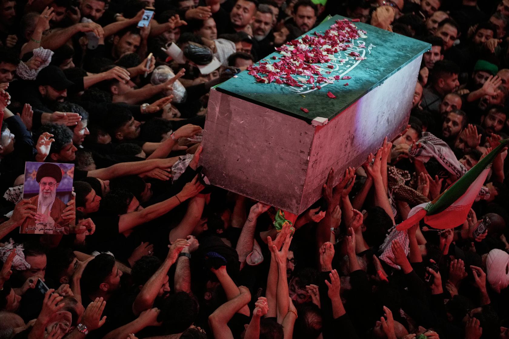 The flower petal-covered coffin of the late Iranian Supreme Leader Ayatollah Ali Khamenei is carried above mourners reaching out to touch it outside the Imam Hussein Shrine in Karbala, Iraq, early Thursday, July 9, 2026. (AP Photo/Khalil Hamra)