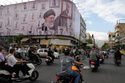 Motorbikes drive past a billboard with graphic showing the late Iranian Supreme Leader Ayatollah Ali Khamenei, who was killed in the U.S. and Israel strikes on Feb. 28, with his framed fist amongst his supporters framed fists in downtown Tehran, Iran, Wednesday, May 6, 2026. (AP Photo/Vahid Salemi)