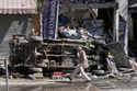 A man passes by a destroyed car and shop on a commercial street that was hit by Israeli airstrikes in Nabatiyeh town, south Lebanon, Thursday, March 5, 2026. (AP Photo/Mohammed Zaatari)