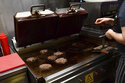 A worker cooks burgers at Zing Burger store in Budapest, Hungary, Monday, Sept. 12, 2022. Richard Kovacs, a business development manager for the Hungarian burger chain, said some of the chain's 15 stores have seen a 750% increase in electricity bills since the beginning of the year – leading to additional monthly costs of up to 1.5 million Hungarian forints ($3,840) per store. (AP Photo/Anna Szilagyi)