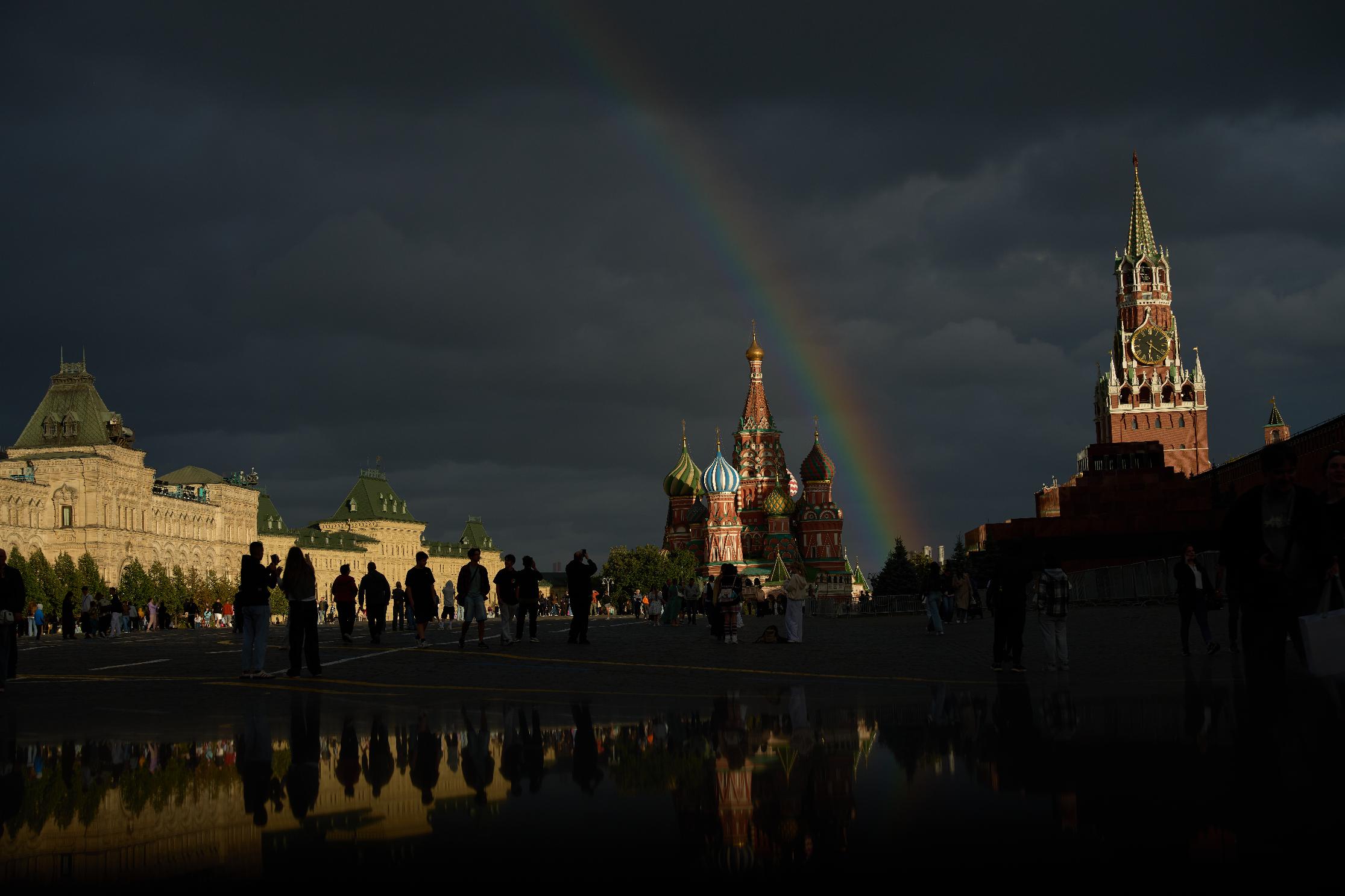 People enjoy a nice view on rainbow, backdropped by the GUM state shop, left, the St. Basil's Cathedral, center, and the Spasskaya Tower, right, walking in Red Square during the golden hour in Moscow, Russia, on Monday, Aug. 24, 2026. (AP Photo/Alexander Zemlianichenko)