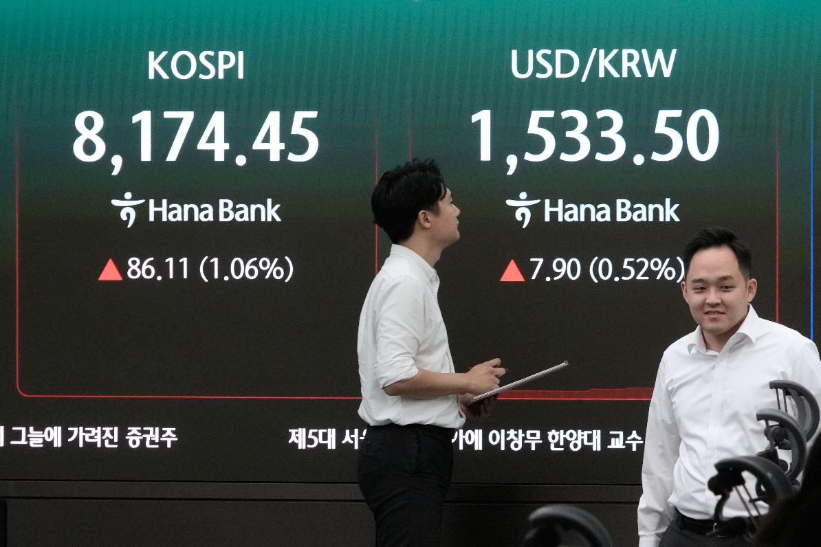 Currency traders pass by a screen showing the Korea Composite Stock Price Index (KOSPI) and the foreign exchange rate between U.S. dollar and South Korean won at the foreign exchange dealing room of the Hana Bank headquarters in Seoul, South Korea, Monday, July 6, 2026. (AP Photo/Ahn Young-joon)