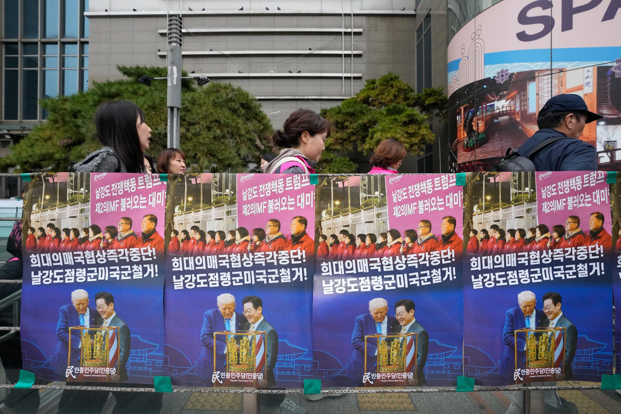Posters showing images of U.S. President Donald Trump and South Korean President Lee Jae Myung are seen at a subway gate during a rally against the government's labor policy and U.S. President Donald Trump's tariffs policy on South Korea, in Seoul, Saturday, Nov. 8 2025. The signs read "Stop the unprecedented negotiations! and Withdraw of US troops!" (AP Photo/Ahn Young-joon)