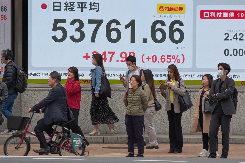People stand in front of an electronic stock board showing Japan's Nikkei index at a securities firm Tuesday, April 7, 2026, in Tokyo. (AP Photo/Eugene Hoshiko)