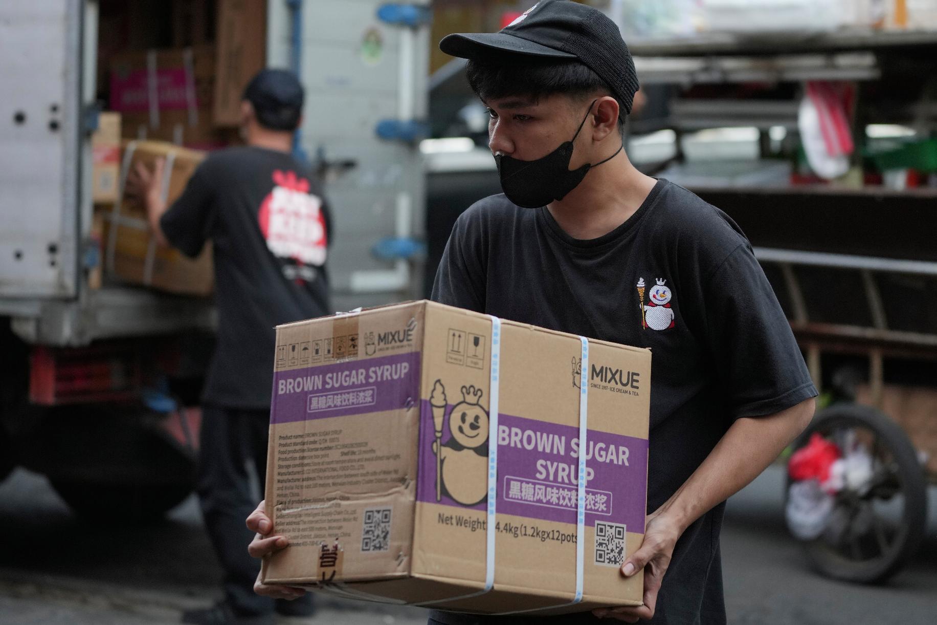A worker carries a box of supplies for a Mixue store in Jakarta, Indonesia, Wednesday, Feb. 19, 2025. (AP Photo/Achmad Ibrahim)