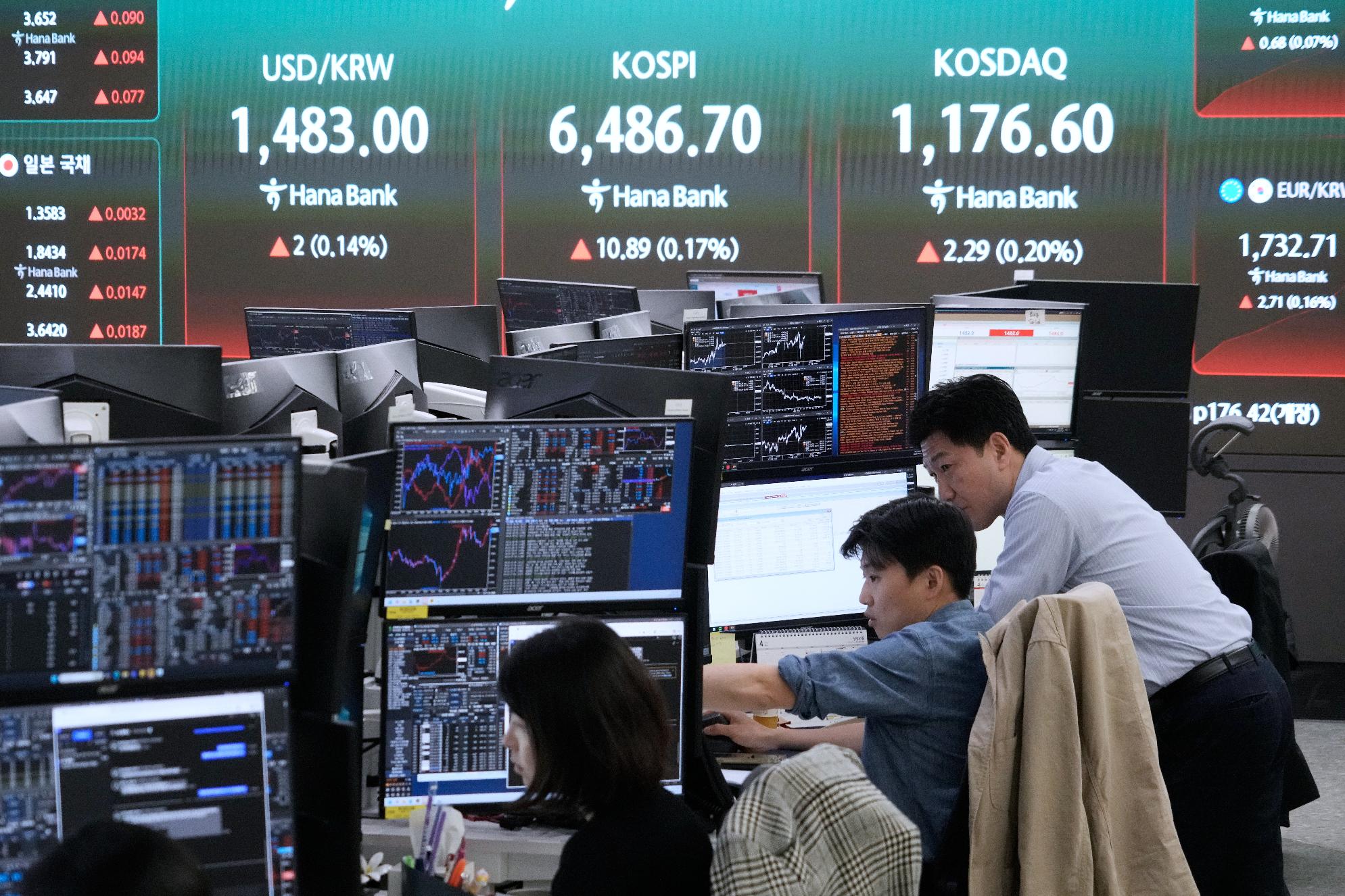 Currency traders watch monitors near a screen showing the Korea Composite Stock Price Index (KOSPI), top center, and the foreign exchange rate between U.S. dollar and South Korean won, top center left, at the foreign exchange dealing room of the Hana Bank headquarters in Seoul, South Korea, Friday, April 24, 2026. (AP Photo/Ahn Young-joon)