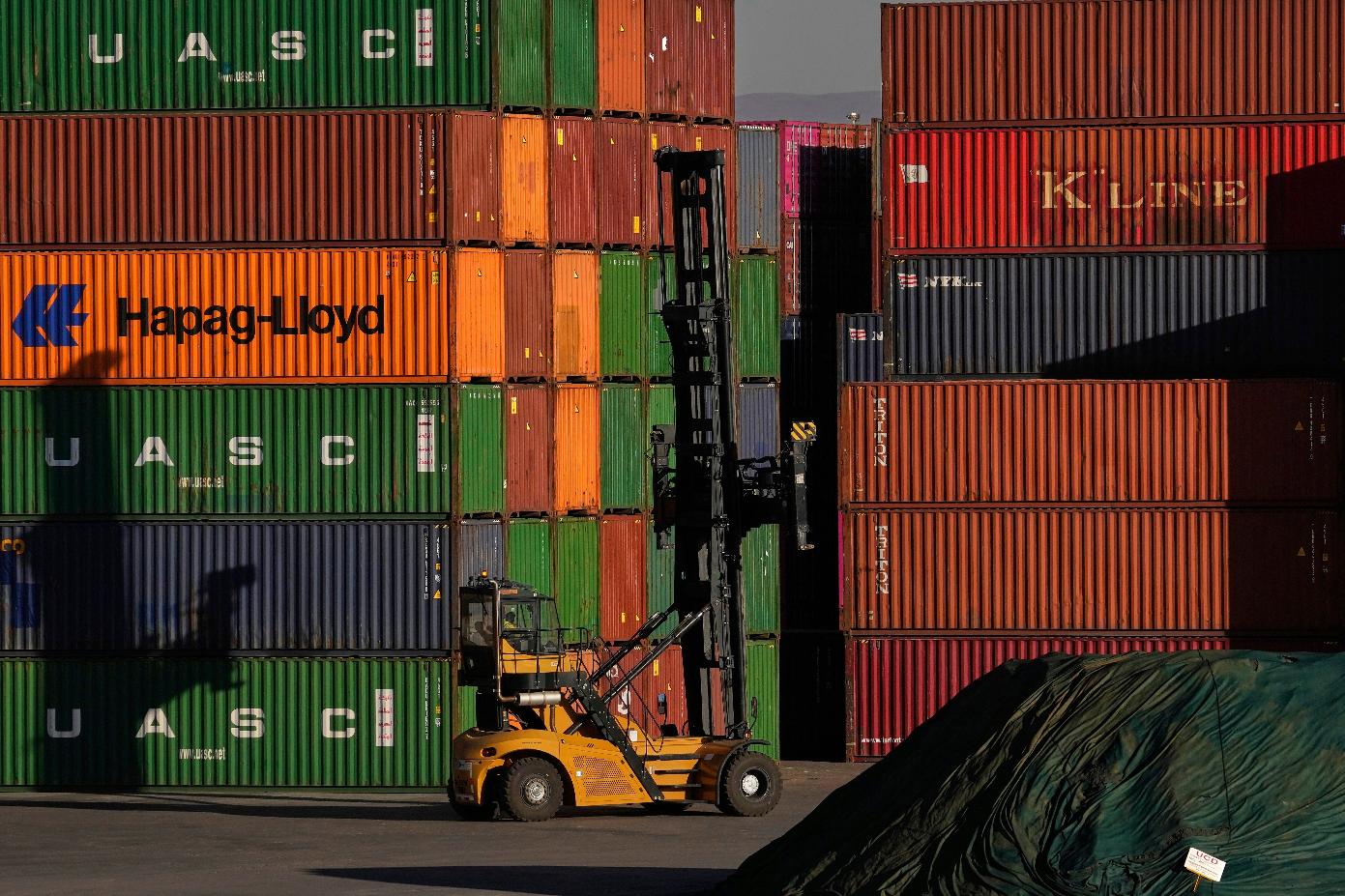 FILE - A heavy machine drives past shipping containers stacked at a depo, in Johannesburg, South Africa, Friday, Aug. 1, 2025. (AP Photo/Themba Hadebe, File)