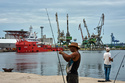 A fisherman prepares his fishing rod in front of the Colombian Navy ship ARC Caribe, docked at a pier in Havana, Cuba, after arriving with humanitarian aid, Friday, June 12, 2926. (AP Photo/Ramon Espinosa)