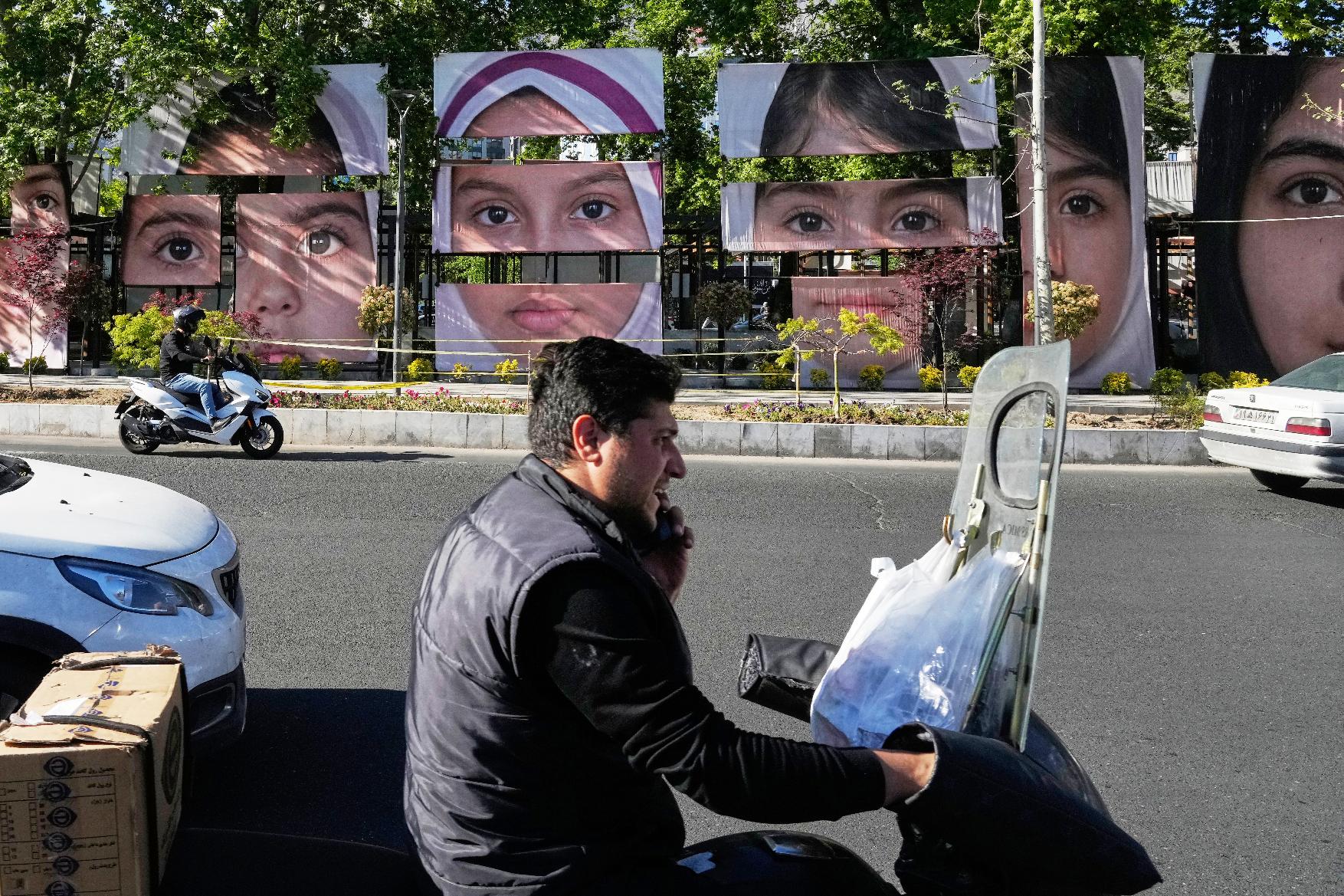 Vehicles drive past banners showing portraits of the school children who were killed during a strike on a school in southern town of Minab on Feb. 28, at Tajrish square in northern Tehran, Iran, Sunday, May 10, 2026. (AP Photo/Vahid Salemi)