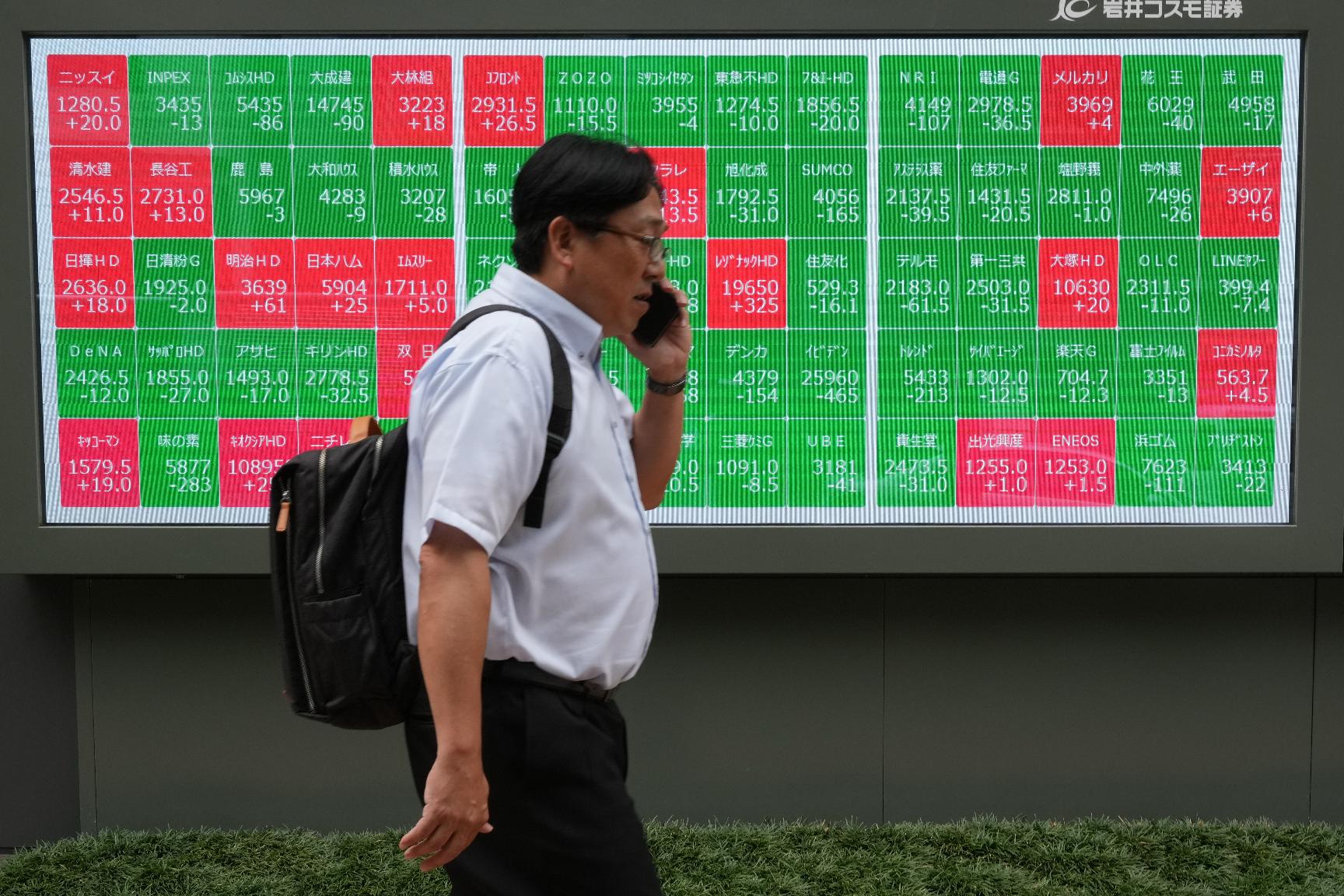 A man walks past a monitor showing stock prices of companies on the Tokyo Stock Exchange in Tokyo, Tuesday, June 23, 2026. (AP Photo/Hiro Komae)