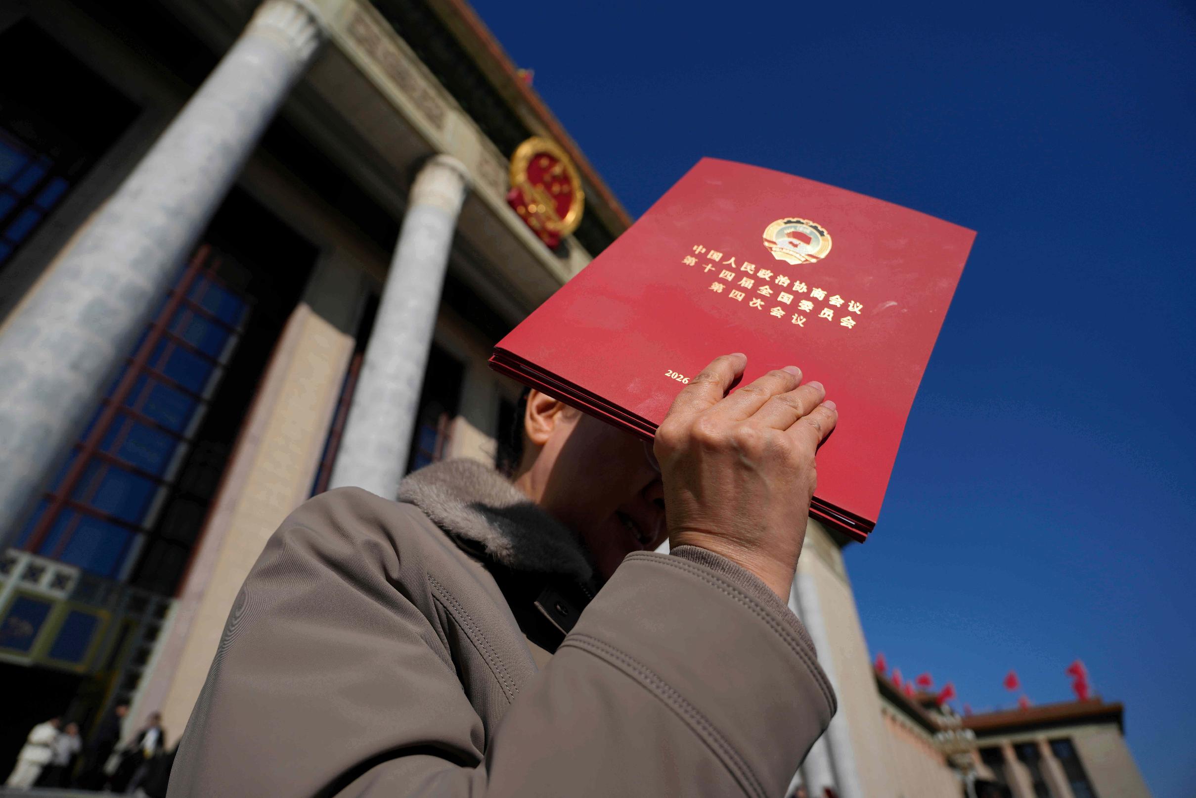 A delegate holds up a red folder as she leaves after the closing ceremony of the Chinese People's Political Consultative Conference (CPPCC), in Beijing, Wednesday, March 11, 2026. (AP Photo/Ng Han Guan)
