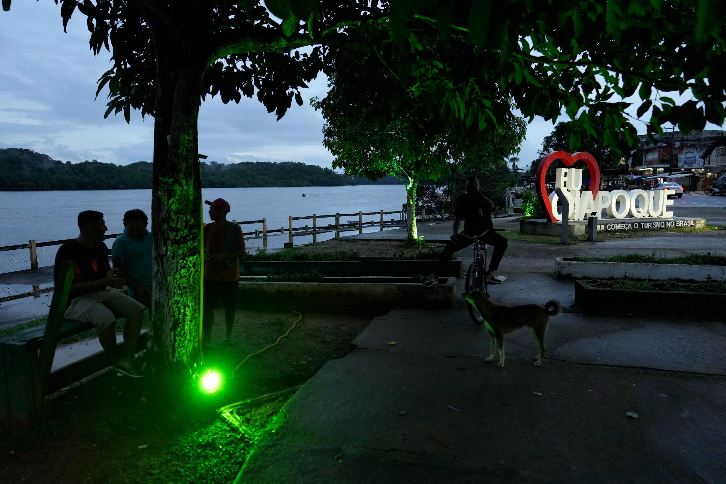 Residents chat at dusk on the banks of the Oiapoque River, in Oiapoque, Amapa state, Brazil, Monday, March 9, 2026. (AP Photo/Eraldo Peres)