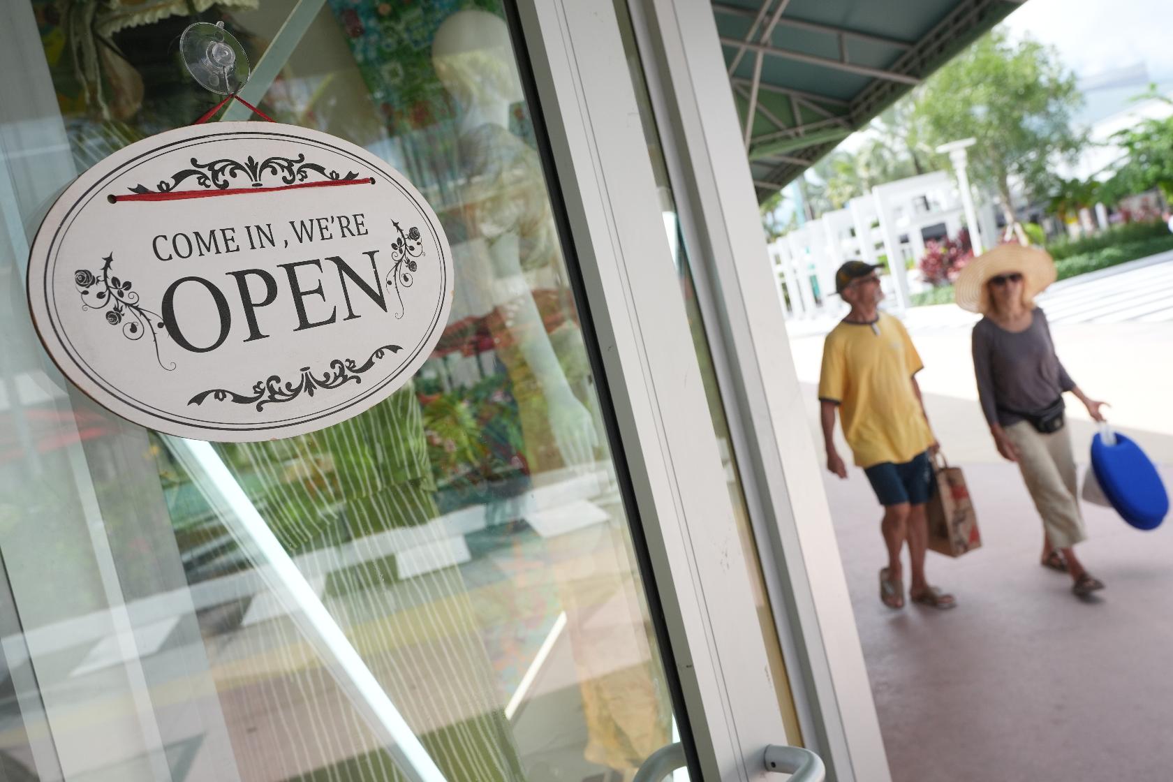 Shoppers walk by a clothing store, Thursday, Sept. 25, 2025, in Miami Beach, Fla. (AP Photo/Marta Lavandier)