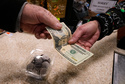 FILE - A shopper pays with cash for a container of candy at a store, Thursday, Dec. 11, 2025, in Salem, N.H. (AP Photo/Charles Krupa, File)