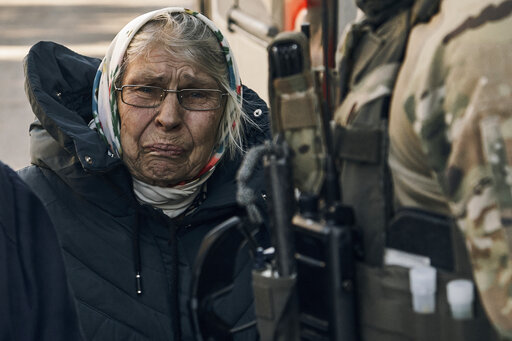 An elderly woman reacts as she leaves her house located in a combat zone in the village of Zarechne, Donetsk region, Monday, Oct. 17, 2022. (AP Photo/LIBKOS)
