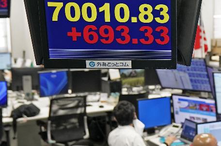 Employee of a foreign exchange dealing company work under an electronic board showing the stock index of Japan's Nikkei 225, in Tokyo Tuesday, Jun 16, 2026. (Kyodo News via AP)