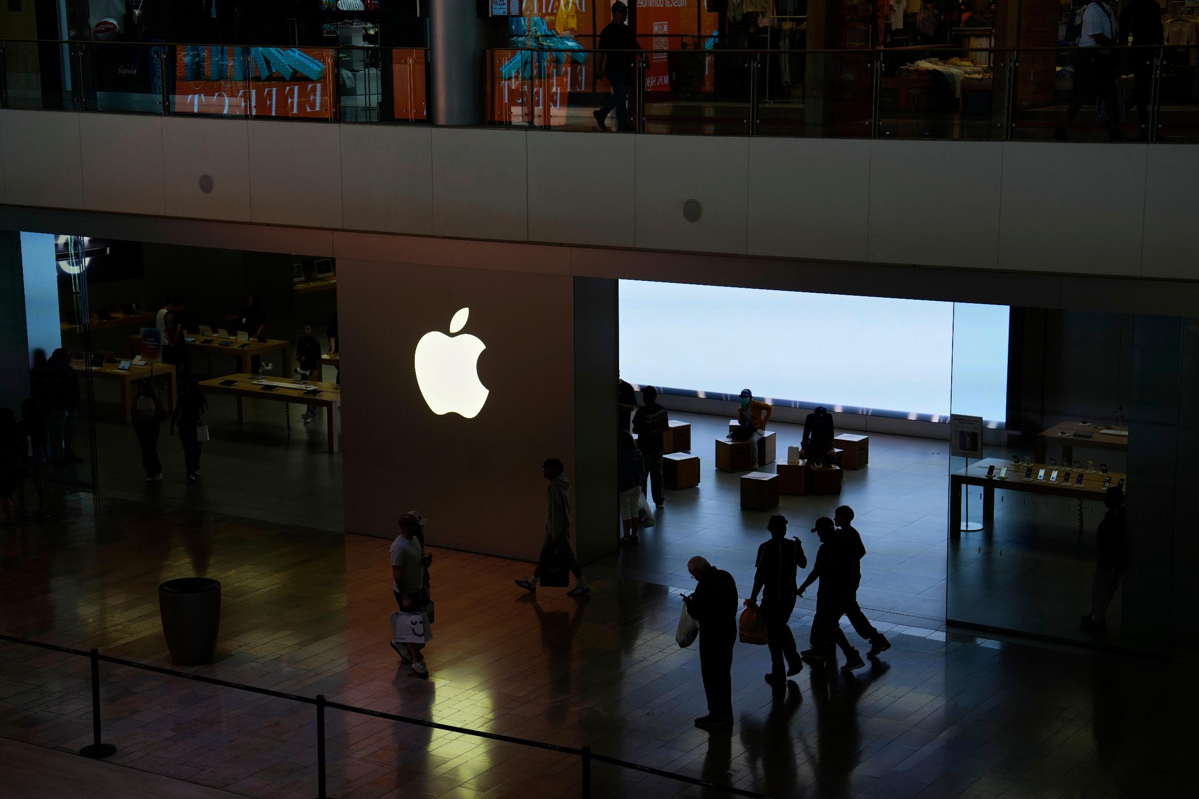 People walk by an Apple store in a mall on the Las Vegas Strip, Tuesday, April 8, 2025, in Las Vegas. (AP Photo/John Locher)