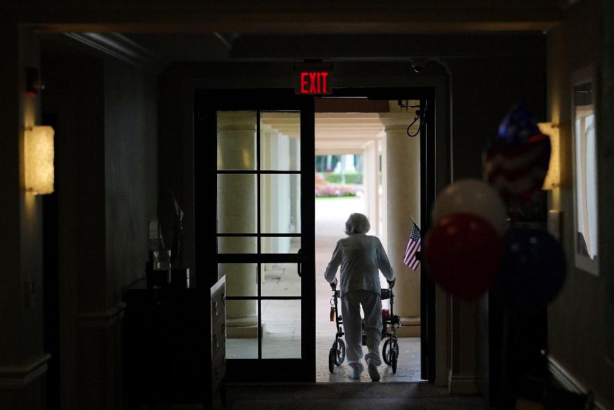 FILE - A woman uses a walker as she exits an assisted living building, July 4, 2025, in Boca Raton, Fla. (AP Photo/Rebecca Blackwell, File)