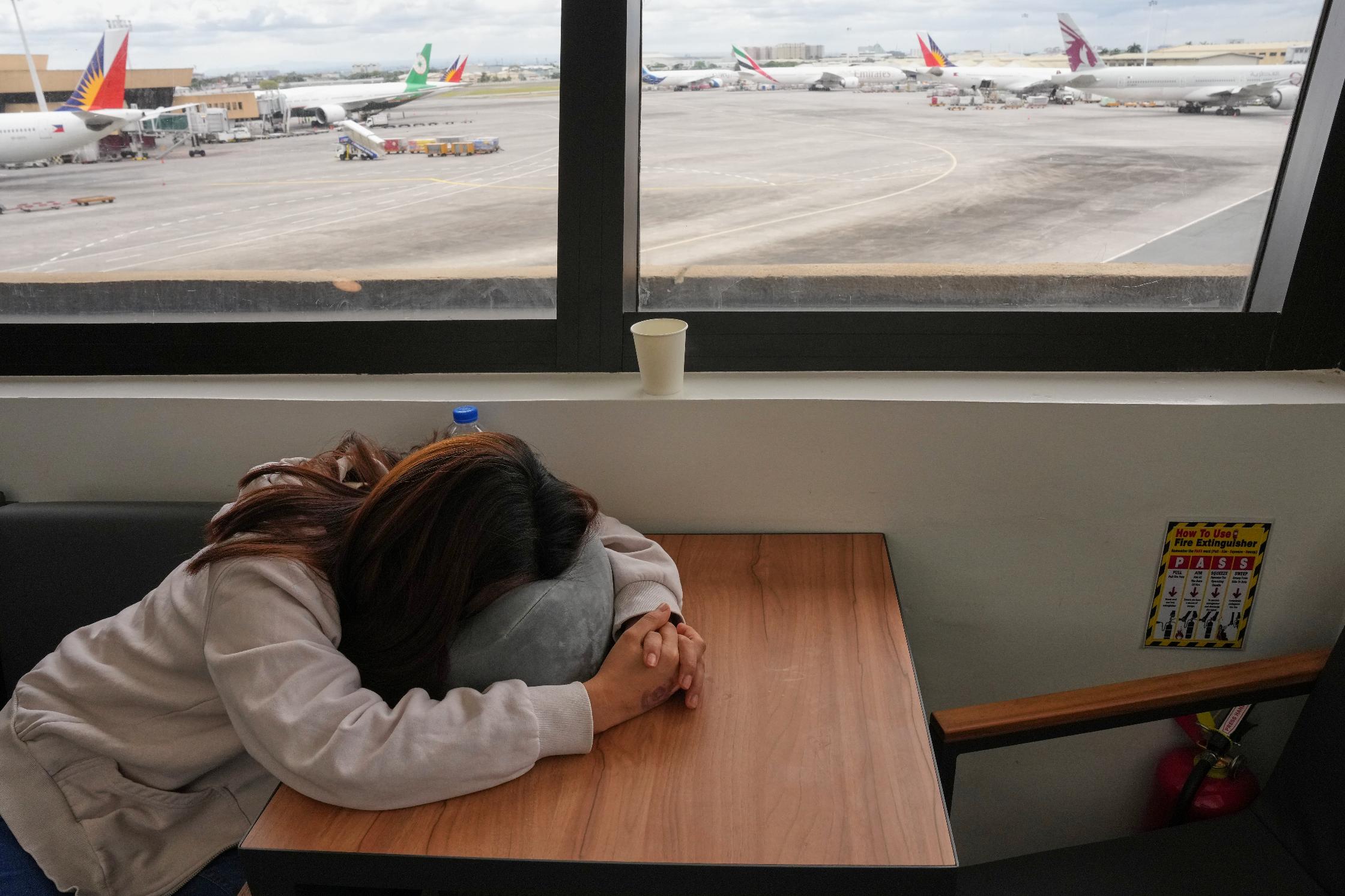 An overseas Filipino worker sleeps as she waits for updates on her cancelled flight to the Middle East at Manila's International Airport, Philippines on Monday, March 2, 2026. (AP Photo/Aaron Favila)