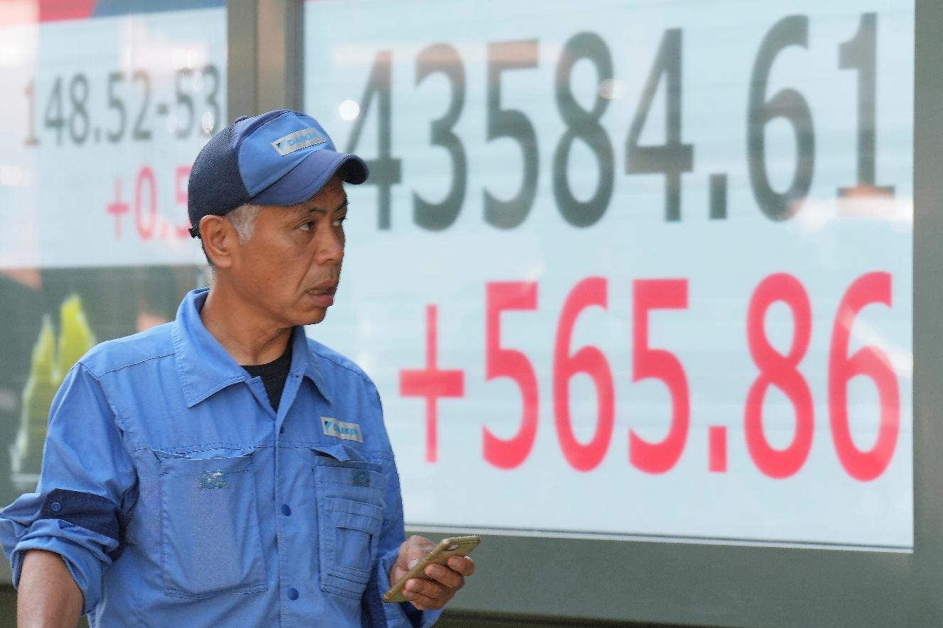 A person walks in front of an electronic stock board showing Japan's Nikkei index at a securities firm Monday, Sept. 8, 2025, in Tokyo. (AP Photo/Eugene Hoshiko)