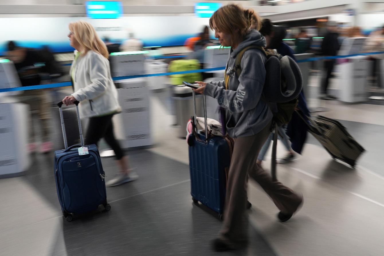 Travelers walk with their luggage through at O'Hare International Airport in Chicago, Friday, May 23, 2025. (AP Photo/Nam Y. Huh)