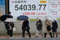 Perople walk in front of an electronic stock board showing Japan's Nikkei index at a securities firm Thursday, April 2, 2026, in Tokyo. (AP Photo/Eugene Hoshiko)