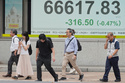 People walk in front of an electronic stock board showing Japan's Nikkei index at a securities firm Tuesday, June 2, 2026, in Tokyo. (AP Photo/Eugene Hoshiko)