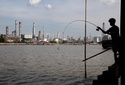 A boy fishes in front of the Bangchak Oil Refinery, home to Thailand's newest sustainable aviation fuel facility, in Bangkok on Jan. 3, 2026. (AP Photo/Anton L. Delgado)