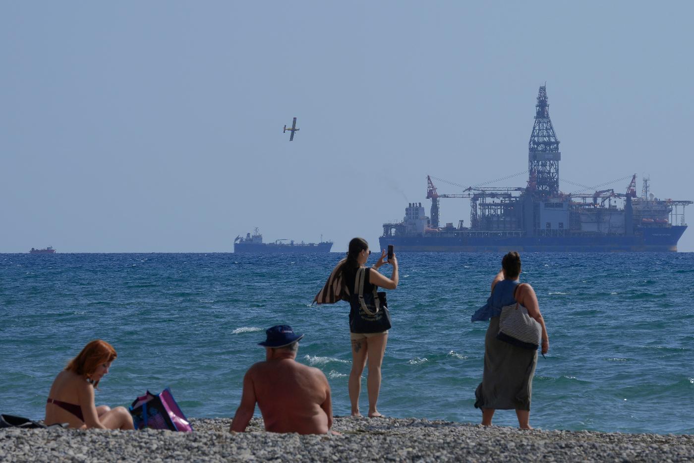 FILE - People on the beach take photos of the 'Tungsten Explored' drilling ship, in the southern coastal city of Larnaca, Cyprus, on Nov. 3, 2021. (AP Photo/Petros Karadjias, File)